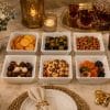 A set of 6 white ribbed square ceramic bowls filled with assorted snacks, beautifully arranged on a dining table with decorative lighting.