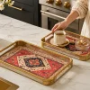 A person holding a beautiful decorative oriental pattern serving tray set of 2 with a gold frame,