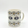A white ceramic mug featuring a repeating boho evil eye and star pattern, displayed on a clean white background