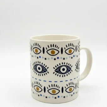 A white ceramic mug featuring a repeating boho evil eye and star pattern, displayed on a clean white background