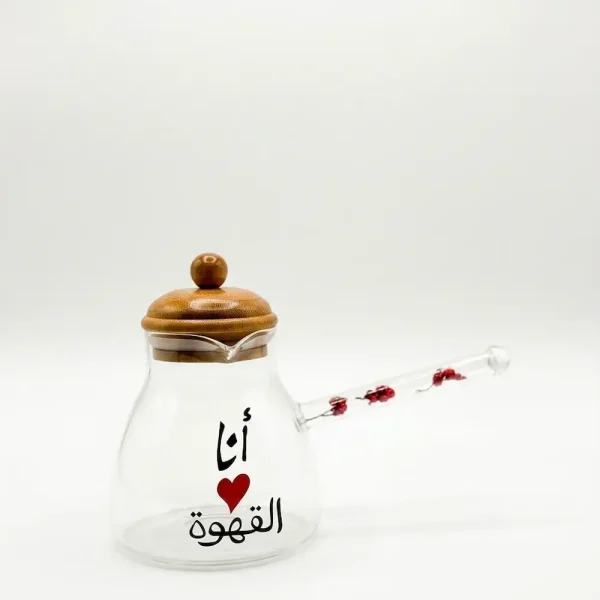 An elegant glass coffee pot with a wooden lid, featuring Arabic calligraphy and red heart art, displayed on a clean white background
