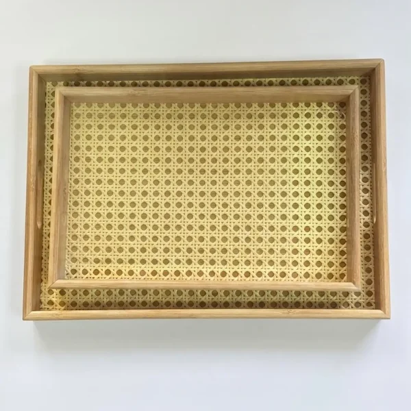 A top-down view of a set of two natural rattan and bamboo serving trays nested inside each other,
