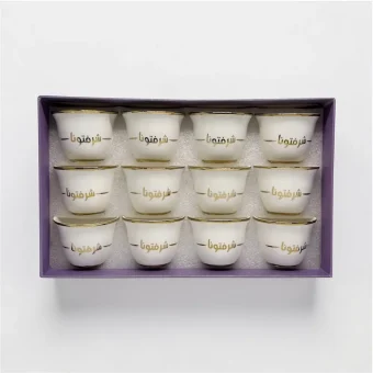 A 12-piece set of white ceramic Arabic coffee cups with gold "شرفتمونا" calligraphy in a gift box,