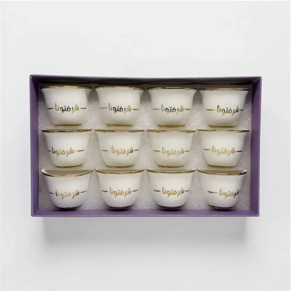 A 12-piece set of white ceramic Arabic coffee cups with gold "شرفتمونا" calligraphy in a gift box,