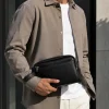 Man carrying black leather travel pouch as everyday essentials bag