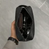 Black leather travel pouch open showing wallet, sunglasses, and keys inside