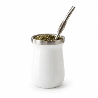 White yerba mate cup with stainless steel rim, filled with mate and supplied with a metal bombilla